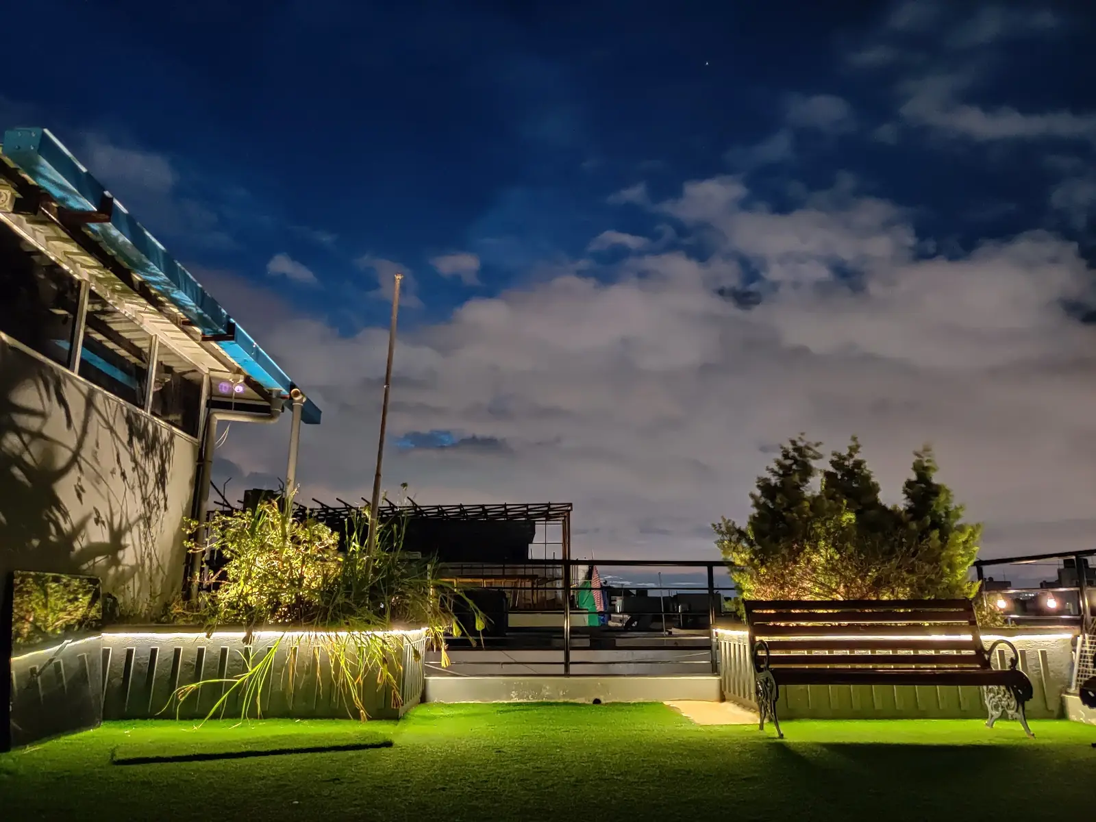 Rooftop garden at dusk with benches and city lights